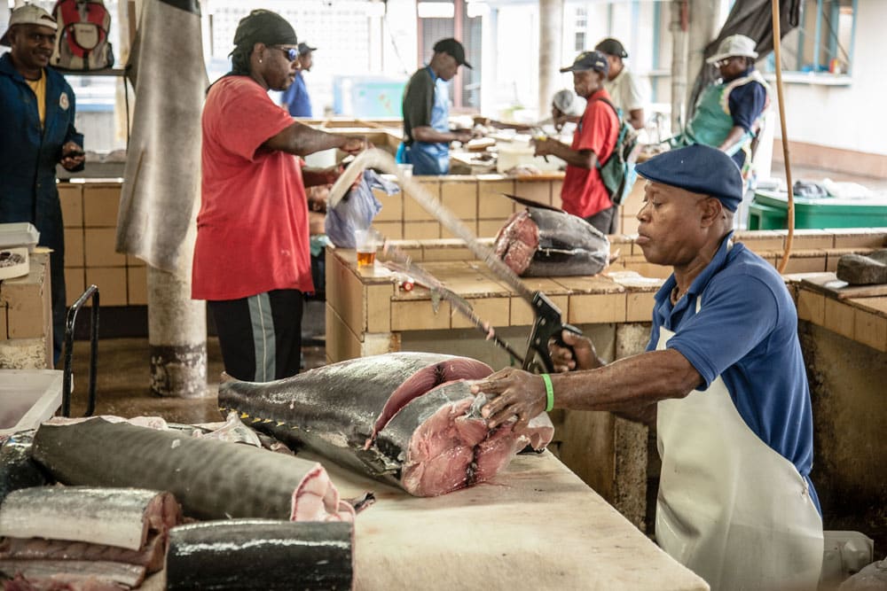 Workers cleaning and cutting fish at a market.