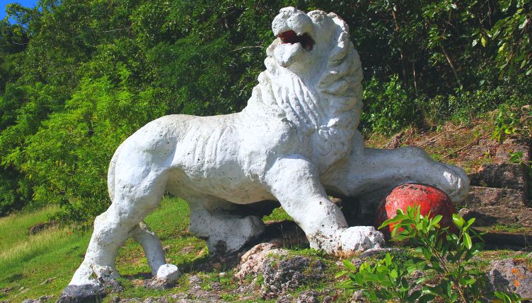 White lion statue with red ball in forest