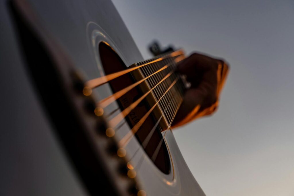 Person playing acoustic guitar strings close-up
