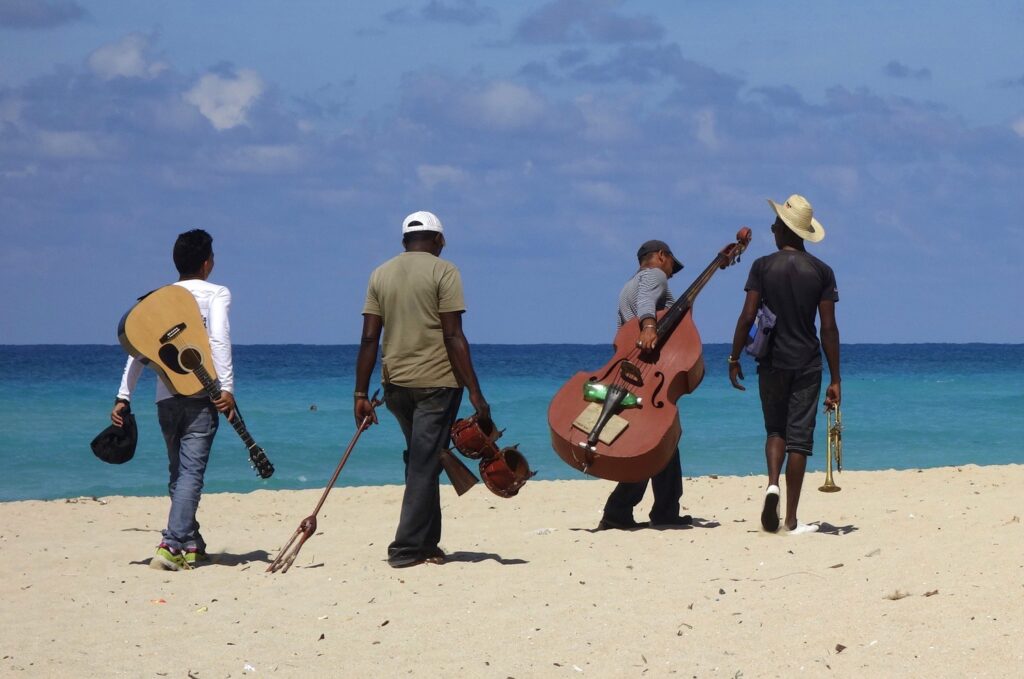 Musicians walking on the beach with instruments.