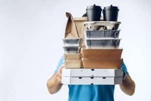 Person holding food delivery packages and coffee cups