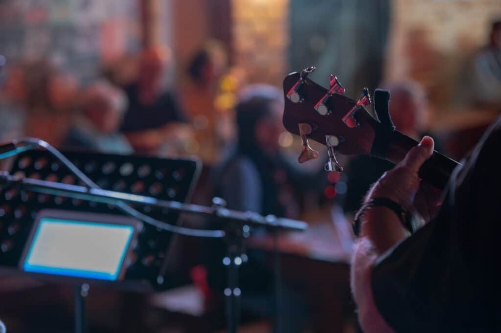 Musician playing guitar in relaxed, dimly lit venue.