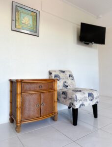 Wicker nightstand and floral chair under wall art